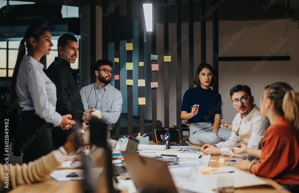 Diverse professionals discussing ideas and projects during a workplace meeting. The atmosphere is dynamic and collaborative, with various people contributing to the conversation in a modern office
